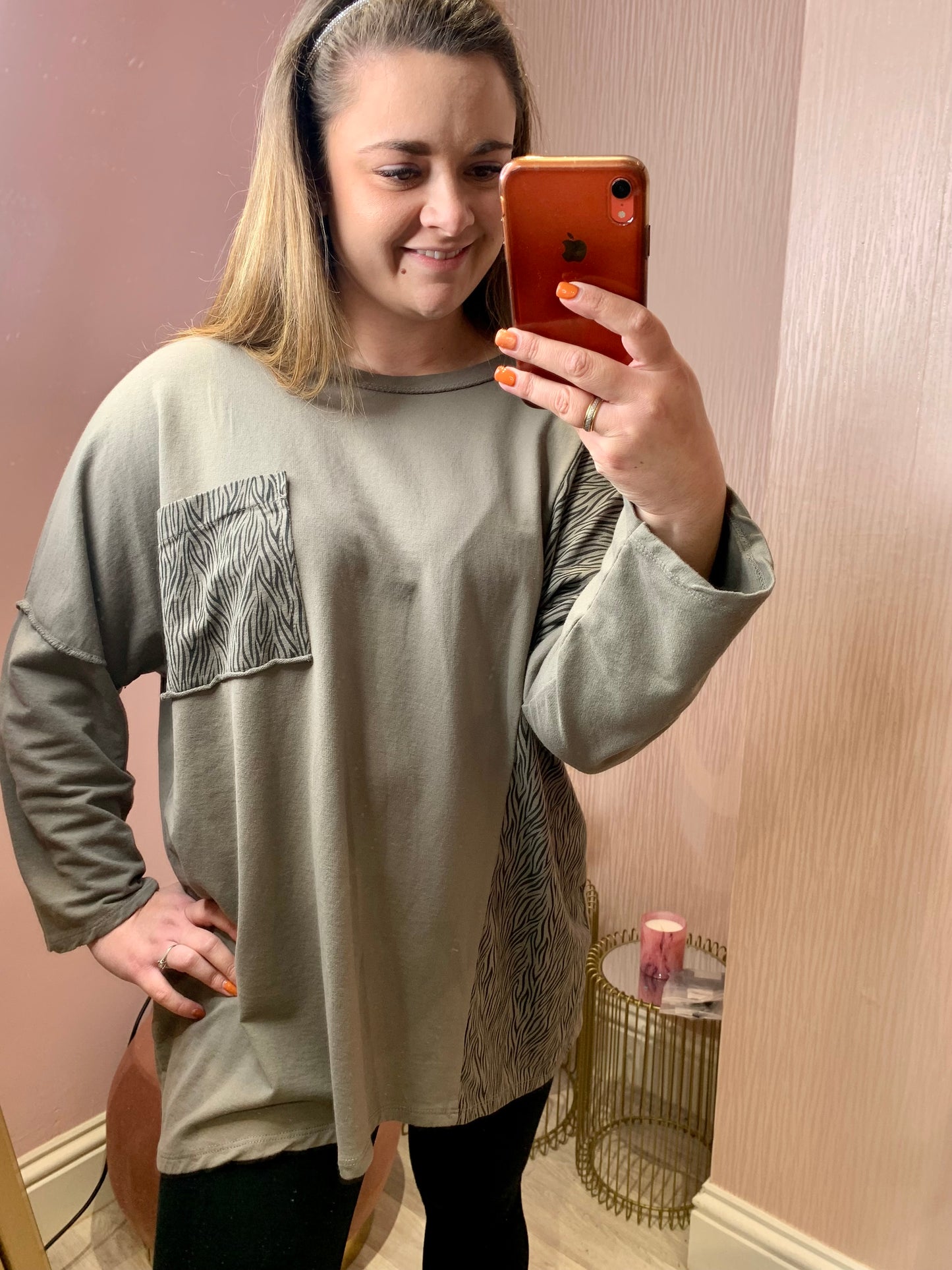 female wearing a grey sweatshirt that has a zebra print trim down the side and on a pocket on the chest. 