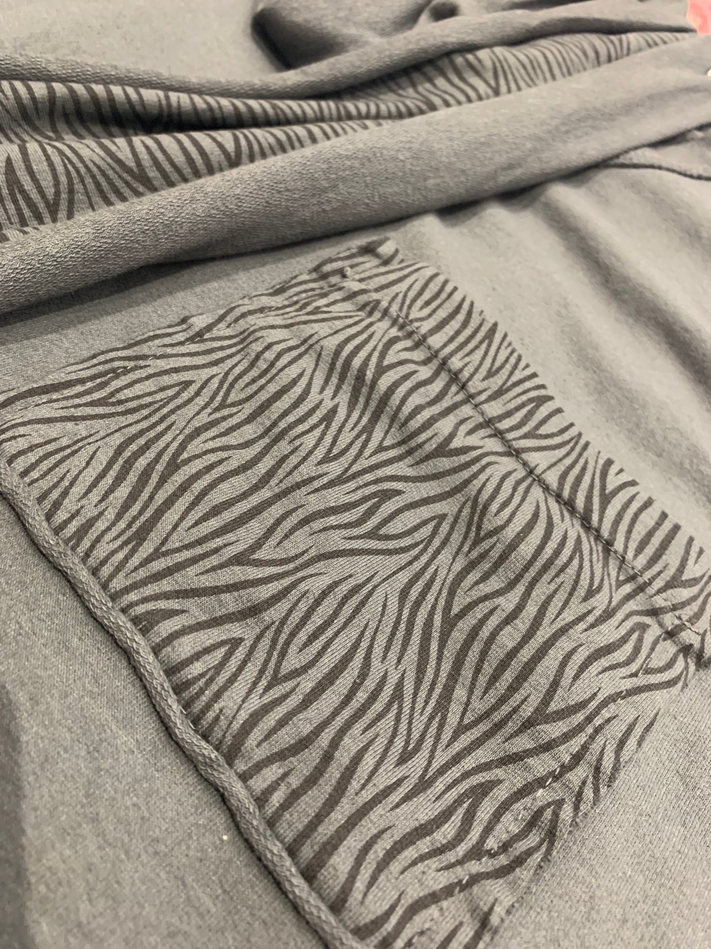 Close up of a dark grey sweatshirt that a pocket with a zebra print trim.
